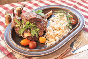 Baked lamb leg on plate with  brown organic rice tomatoes, ,parsley