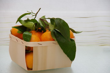 clementines with green leaves in a box