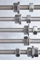 Metal bolt nuts and washers with metric thread on grey background