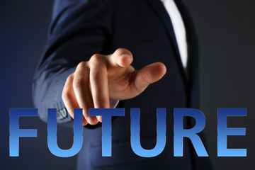 Future concept. Businessman in suit points on word on dark background