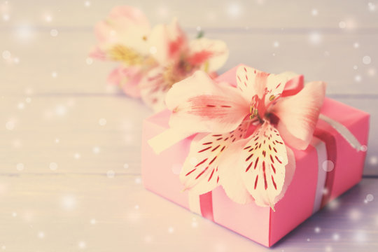 Beautiful gift box with fresh flower on wooden surface background