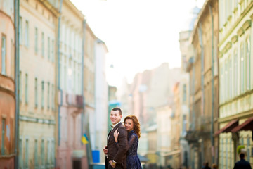 Fototapeta premium grom holding hand bride with red hair near wall outdoors Lviv