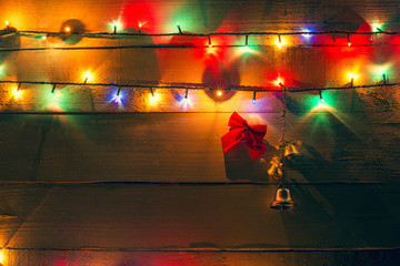 Christmas lights and bells on wood background