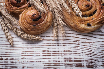 Sweet rolls with raisins golden wheat ears on vintage wooden boa