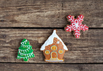 Homemade gingerbread cookies in the shape of house with snow, Christmas tree and snowflake on the wooden table. Space for text and selective focus.