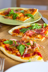 Slices of italian style pizza with arugula and prosciutto