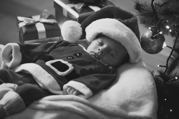 Monochrome portrait of sleeping baby boy in Santa costume