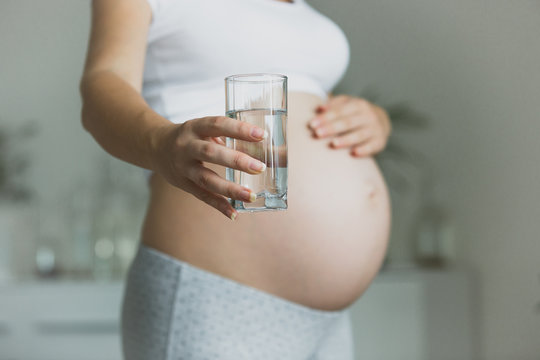 Closeup Of Pregnant Woman Holding Glass Of Water