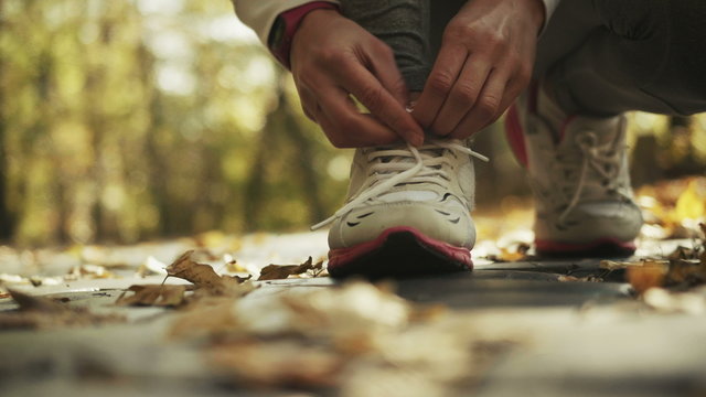 Young sporty woman preparing to run in a beautiful autumn forest, wellness concept.