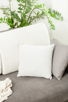 Closeup of white decorative cushion lying on gray sofa at living