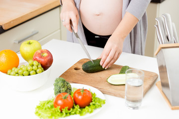 Obraz na płótnie Canvas Closeup of pregnant woman making salad from vegetables