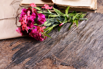 Old book with beautiful flowers and envelopes on wooden table close up