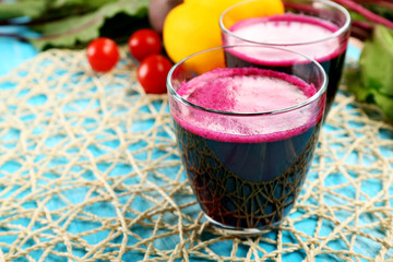 Glasses of beet juice with vegetables on table close up