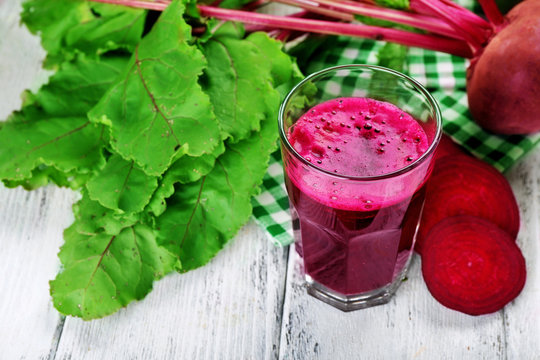 Glass of beet juice with vegetables on table close up