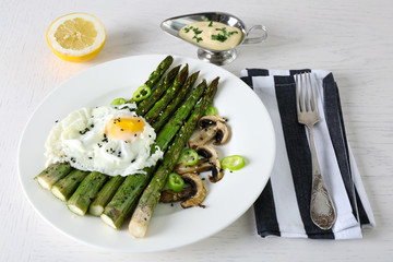 Roasted asparagus with poached egg on plate on table background