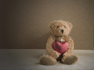 Teddy bear sitting with red heart background