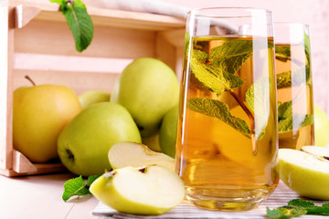 Glasses of apple juice with fruits and fresh mint on table close up