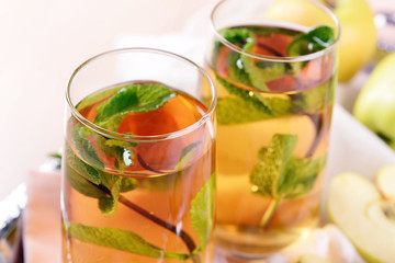 Glasses of apple juice with fruits and fresh mint on table close up