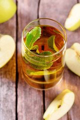 Glass of apple juice with fruits and fresh mint on table close up