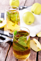 Glasses of apple juice with fruits and fresh mint on table close up