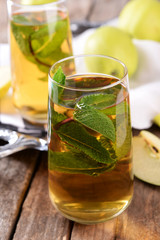 Glass of apple juice with fruits and fresh mint on table close up