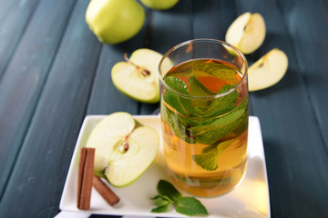 Glass of apple juice with fruits and fresh mint on table close up