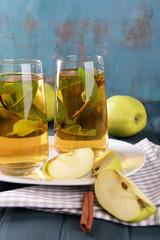 Glasses of apple juice with fruits and fresh mint on table close up