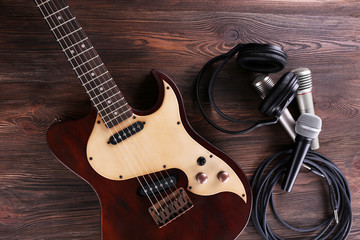 Fototapeta premium Electric guitar with microphones and headphones on wooden table close up