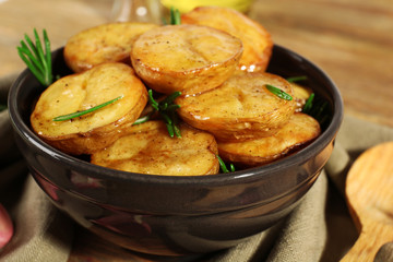 Delicious baked potato with rosemary in bowl on table close up