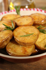 Delicious baked potato with rosemary in bowl on table close up