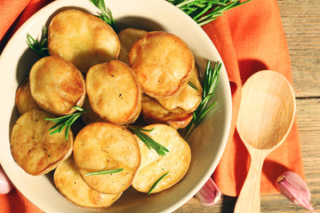 Delicious baked potato with rosemary in bowl on table close up