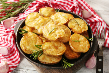Delicious baked potato with rosemary in frying pan on table close up