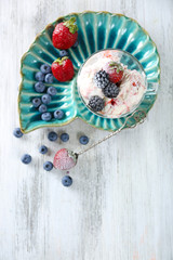 Delicious ice cream with fresh frozen berries, on color wooden background