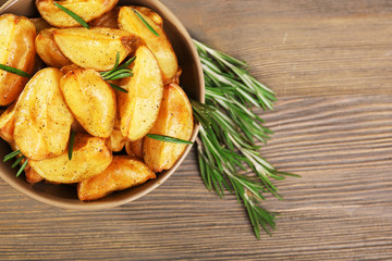 Baked potato wedges on wooden table, top view