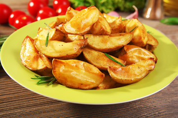 Baked potato wedges on wooden table, closeup