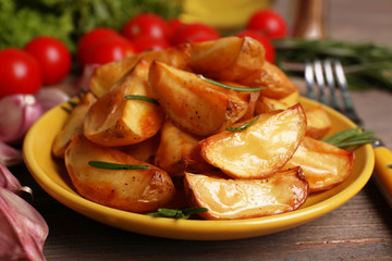 Baked potato wedges on wooden table, closeup