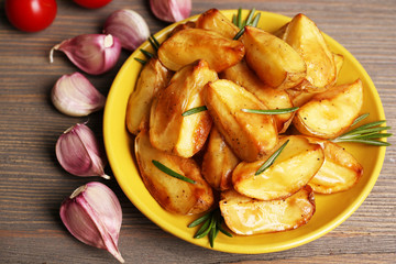 Baked potato wedges on wooden table, closeup