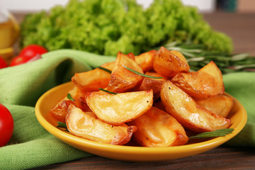 Baked potato wedges on wooden table, closeup