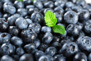 Tasty ripe blueberries with green leaves close up