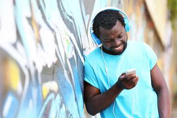 African American man with headphones on graffiti wall background