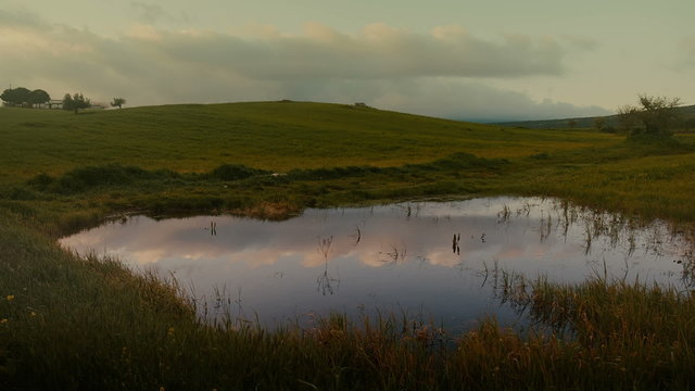 Spring landscape in the morning/dawn, countryside sky and clouds reflected on pond