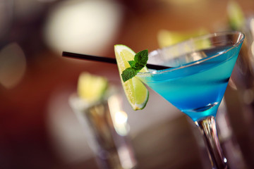 Glasses of cocktails on bar background