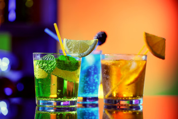 Glasses of cocktails on bar background