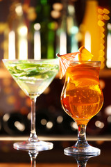 Glasses of cocktails on bar background