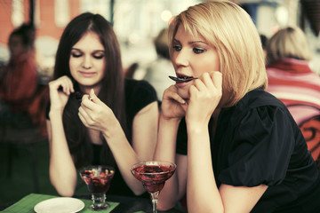 Two young women eating dessert at sidewalk cafe