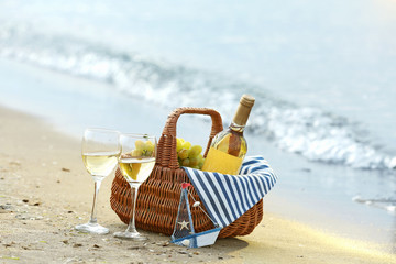 Fototapeta na wymiar Picnic basket with bottle of wine on sand beach