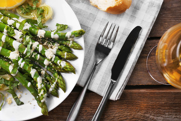 Served wooden table with asparagus dish and wine, close up