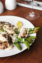 Delicious dish with asparagus and mushrooms on served wooden table in the restaurant, close up