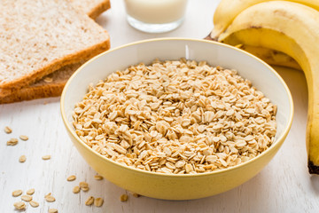 a bowl full of oatmeal, with banana, milk, and dry bread