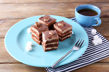 Sweet chocolate cake on blue plate on wooden table